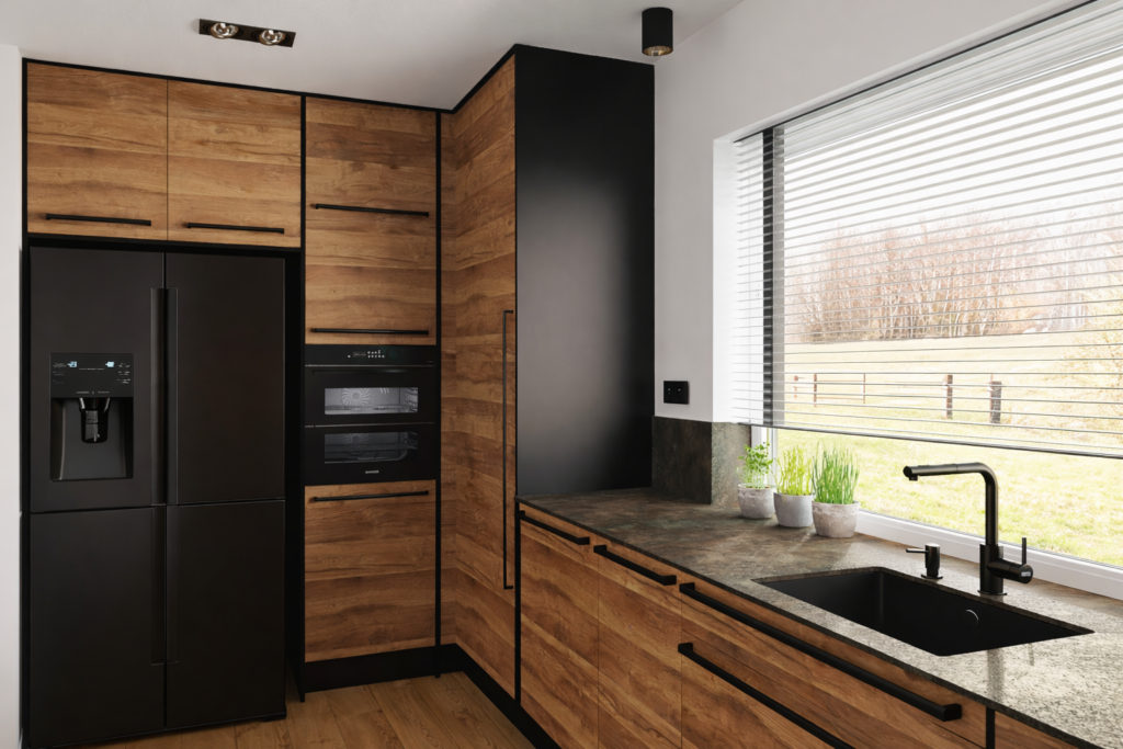 Nowoczesna kuchnia z drewnianymi szafkami i czarnymi urządzeniami AGD, w tym lodówką side-by-side i piekarnikiem. Pod oknem z żaluzjami znajduje się blat roboczy z czarnym zlewem i kranem w kolorze czarnym.